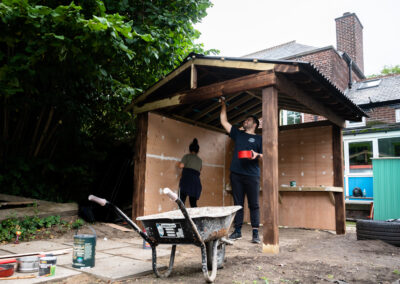 Volunteers building the new play area, designed by the children who will be using it. Here, they are building a shed-like structure.