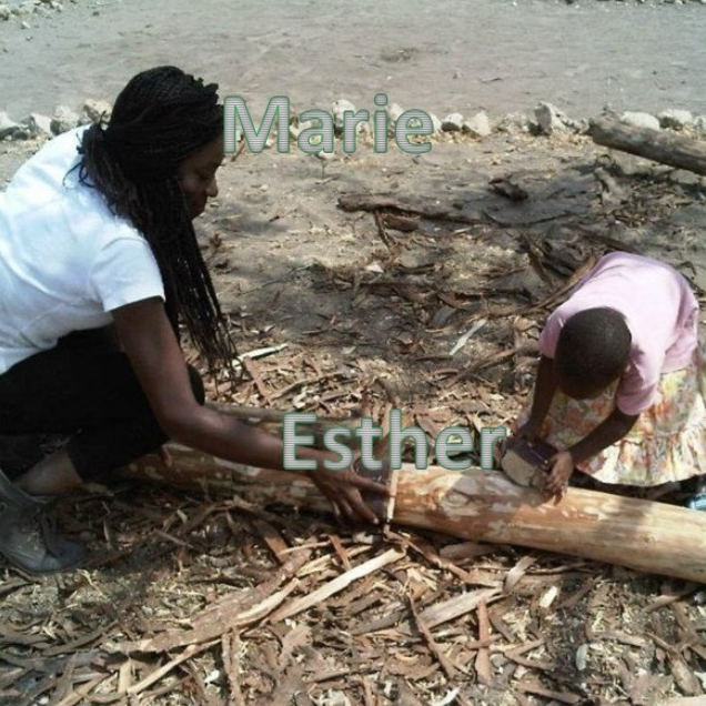 A photo of Marie holding a piece of wood, while Esther sands down the wood